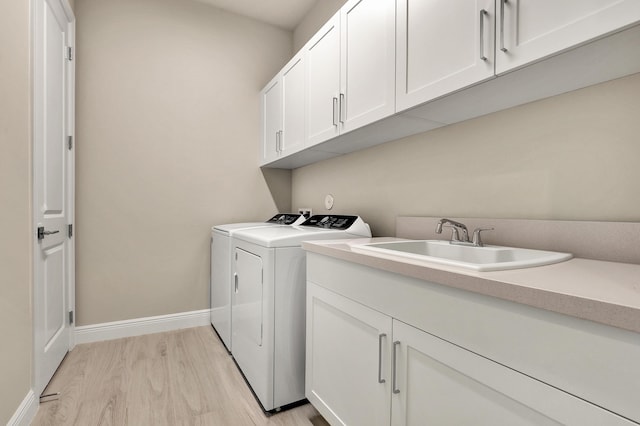 washroom featuring cabinets, sink, light wood-type flooring, and independent washer and dryer