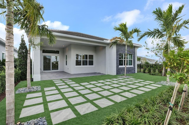 rear view of property featuring a yard and a patio area