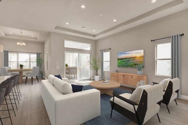 living room featuring a raised ceiling, an inviting chandelier, and light hardwood / wood-style flooring