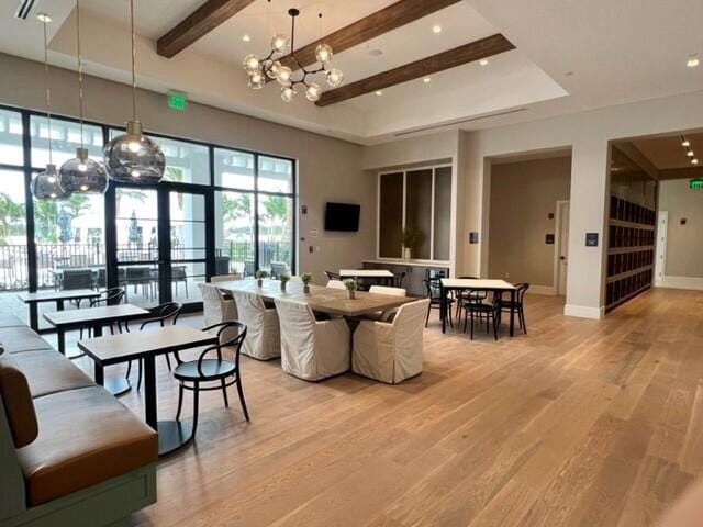 dining space featuring beamed ceiling, light hardwood / wood-style flooring, and a notable chandelier