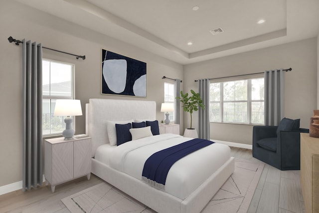 bedroom with light wood-type flooring, a raised ceiling, and multiple windows