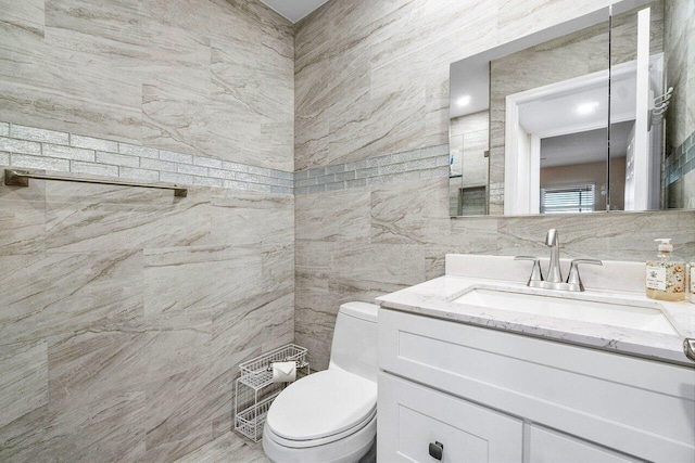 bathroom with tile walls, vanity, and toilet