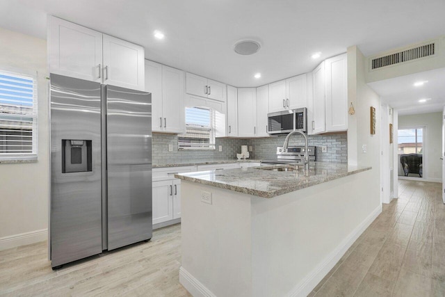 kitchen featuring white cabinets, light hardwood / wood-style floors, plenty of natural light, and appliances with stainless steel finishes