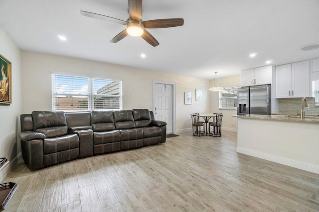 living room featuring ceiling fan, sink, and light wood-type flooring