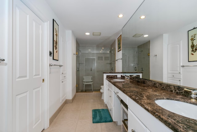 bathroom with tile patterned floors, toilet, walk in shower, and double sink vanity