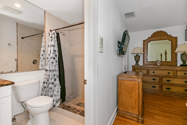 bathroom with a textured ceiling, toilet, curtained shower, hardwood / wood-style flooring, and vanity