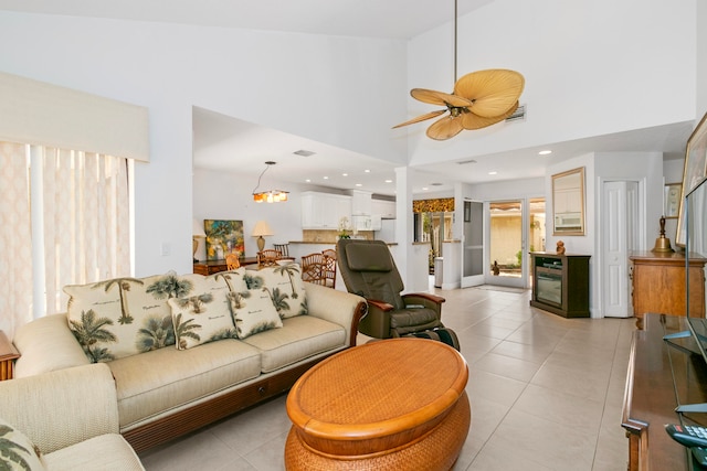 tiled living room featuring ceiling fan with notable chandelier and a high ceiling