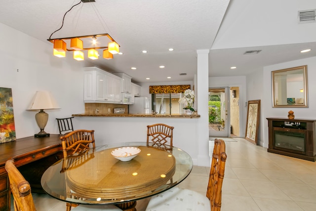 dining room featuring light tile patterned flooring and ornate columns