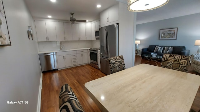 kitchen with appliances with stainless steel finishes, sink, white cabinetry, and dark hardwood / wood-style floors