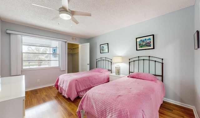 bedroom with a closet, a walk in closet, hardwood / wood-style flooring, and ceiling fan