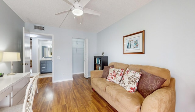 living room featuring ceiling fan, wood-type flooring, and a textured ceiling