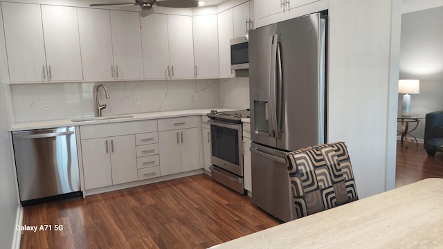 kitchen featuring ceiling fan, stainless steel appliances, tasteful backsplash, dark wood-type flooring, and sink