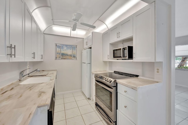 kitchen featuring stainless steel appliances, white cabinets, sink, light tile patterned floors, and ceiling fan