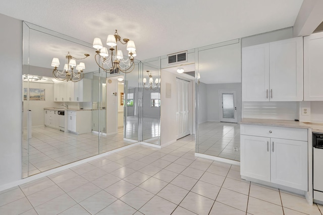 kitchen with a notable chandelier, light tile patterned flooring, and white cabinetry