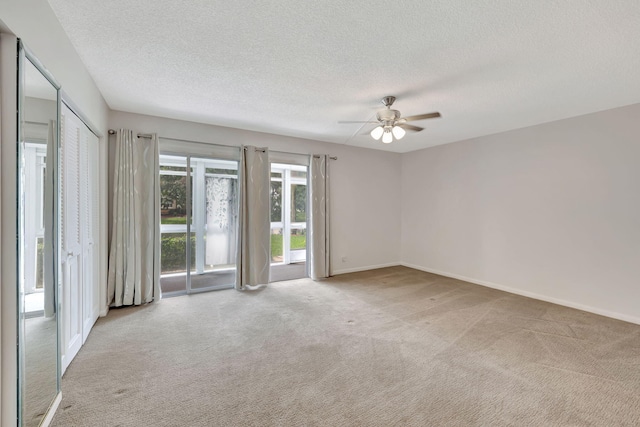 carpeted spare room with a textured ceiling and ceiling fan