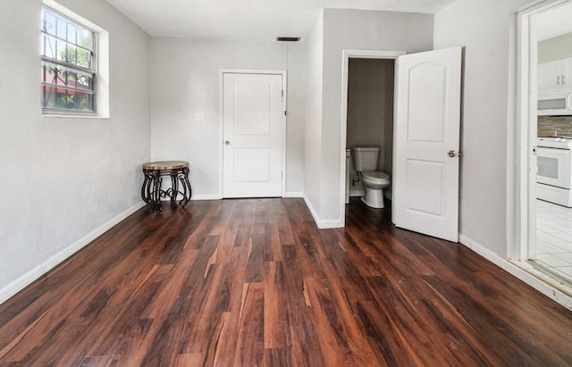 unfurnished bedroom featuring dark wood-type flooring and ensuite bathroom