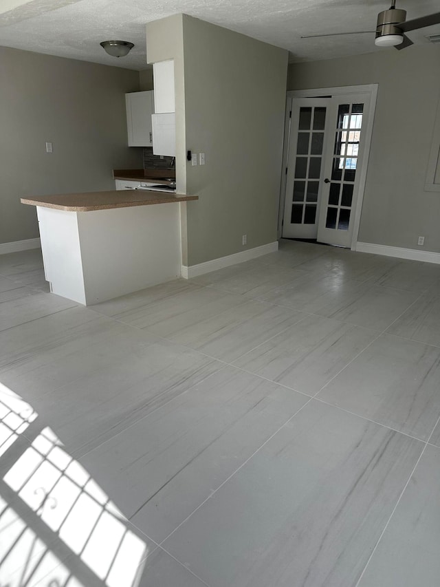 unfurnished living room featuring light tile patterned floors, a textured ceiling, ceiling fan, and french doors