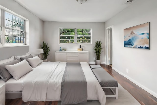 bedroom featuring multiple windows and dark hardwood / wood-style flooring