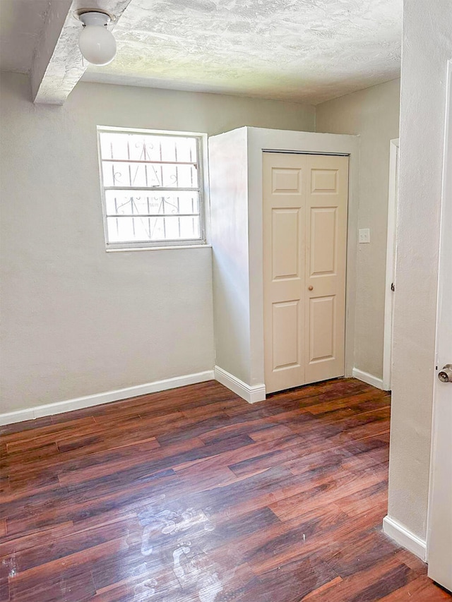 unfurnished room with a textured ceiling and wood-type flooring