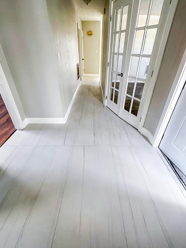 corridor with light hardwood / wood-style floors and french doors