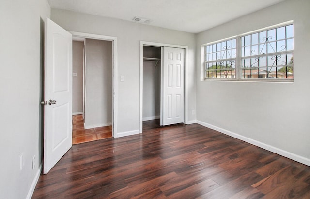 unfurnished bedroom featuring dark hardwood / wood-style flooring and a closet