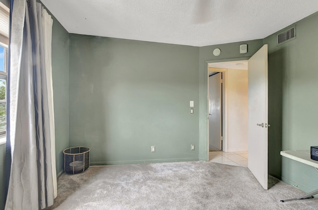 spare room with a textured ceiling and light carpet