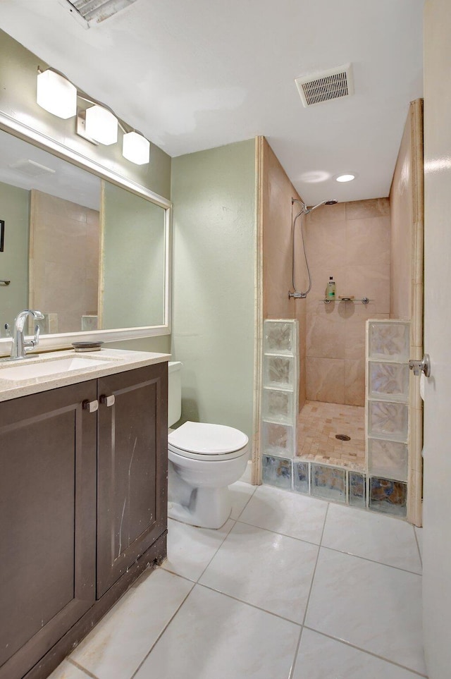 bathroom with tiled shower, tile patterned floors, vanity, and toilet