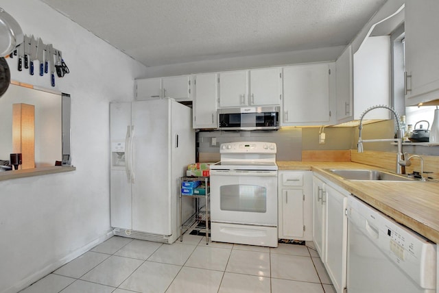 kitchen with white cabinets, sink, white appliances, and light tile patterned floors