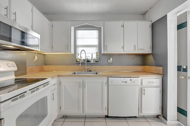 kitchen featuring a textured ceiling, white appliances, light tile patterned floors, sink, and white cabinetry