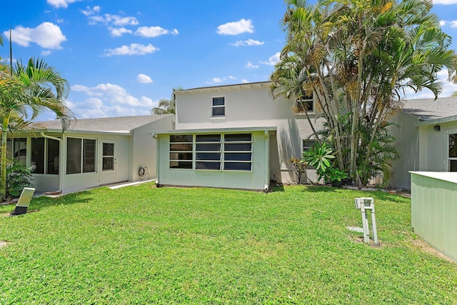 back of property with a sunroom and a lawn