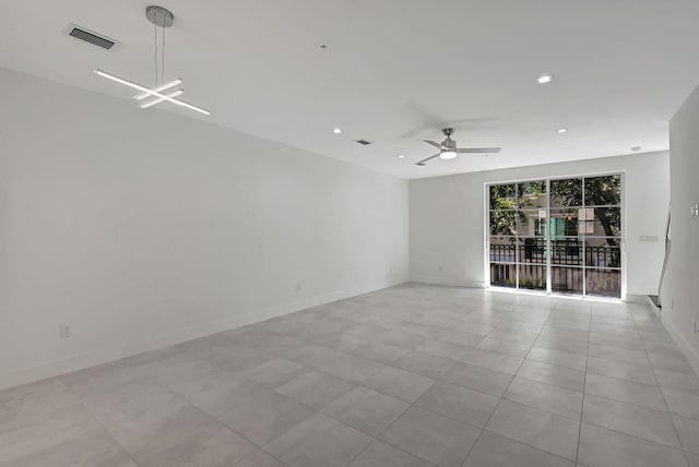 tiled empty room featuring ceiling fan with notable chandelier