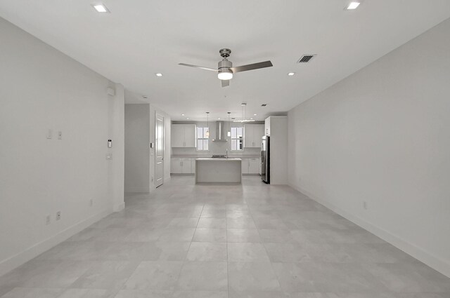 unfurnished living room with sink, light tile patterned floors, and ceiling fan