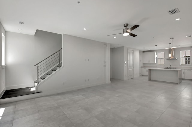 unfurnished living room with sink, light tile patterned floors, and ceiling fan