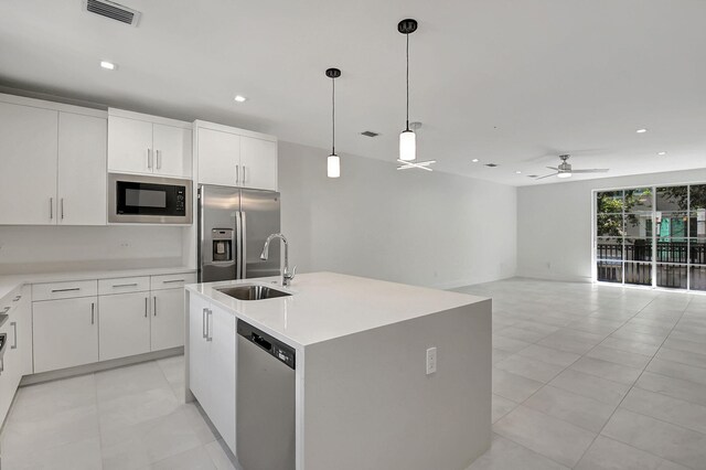 kitchen featuring light tile patterned flooring, stainless steel appliances, an island with sink, and ceiling fan