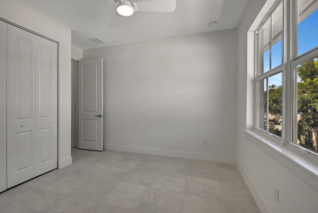 unfurnished bedroom with a closet, multiple windows, ceiling fan, and light tile patterned floors