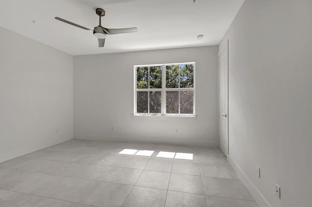 empty room with ceiling fan and light tile patterned floors