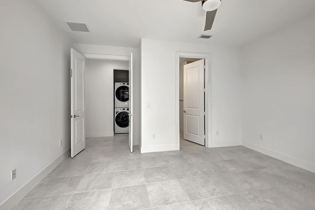 unfurnished bedroom with stacked washer and dryer, light tile patterned floors, and ceiling fan