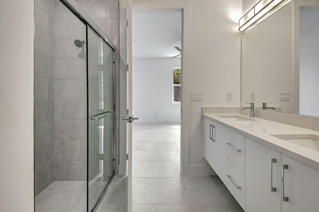 bathroom with a shower with shower door, double vanity, and tile patterned floors