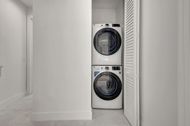 laundry room with stacked washer and dryer and light tile patterned floors