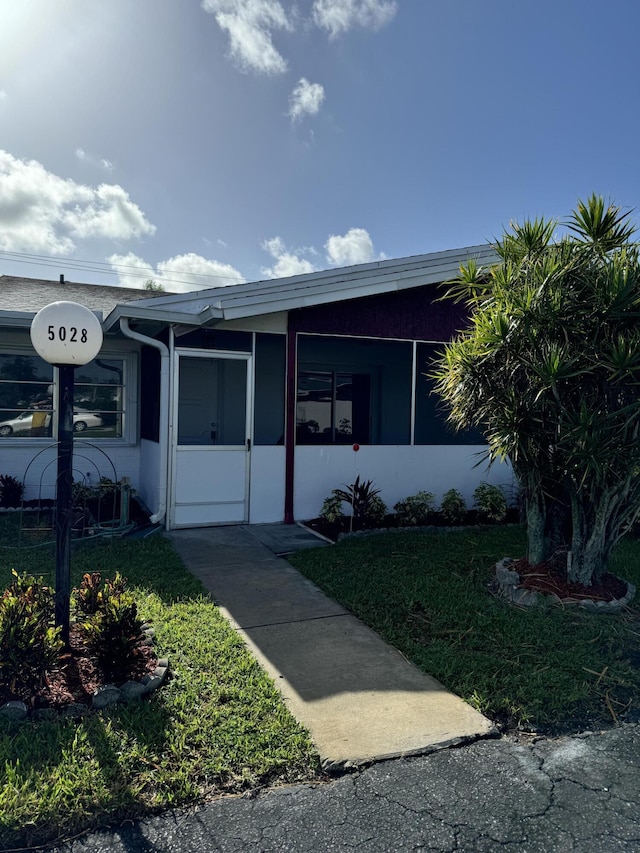 view of front of property featuring a front yard and a sunroom