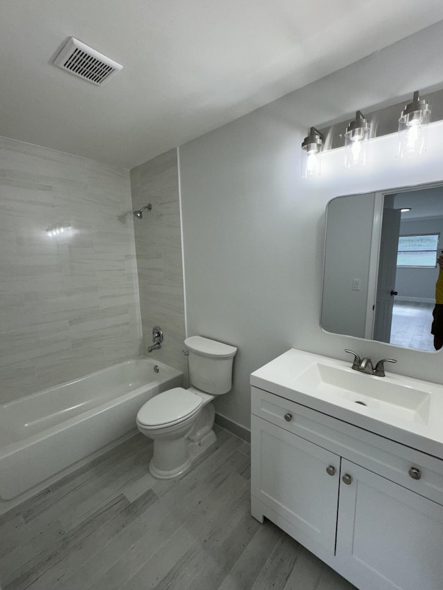 full bathroom with hardwood / wood-style floors, toilet, vanity, and tiled shower / bath