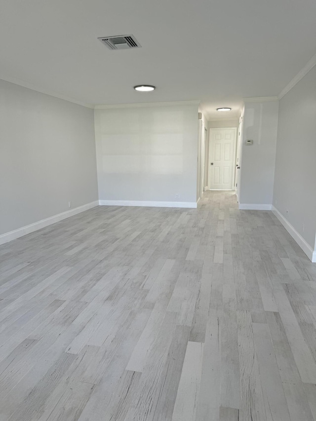 spare room featuring crown molding and light hardwood / wood-style floors