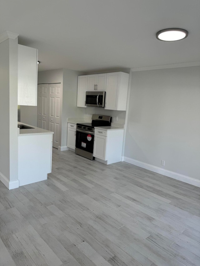 kitchen featuring sink, stainless steel appliances, white cabinetry, and light wood-type flooring