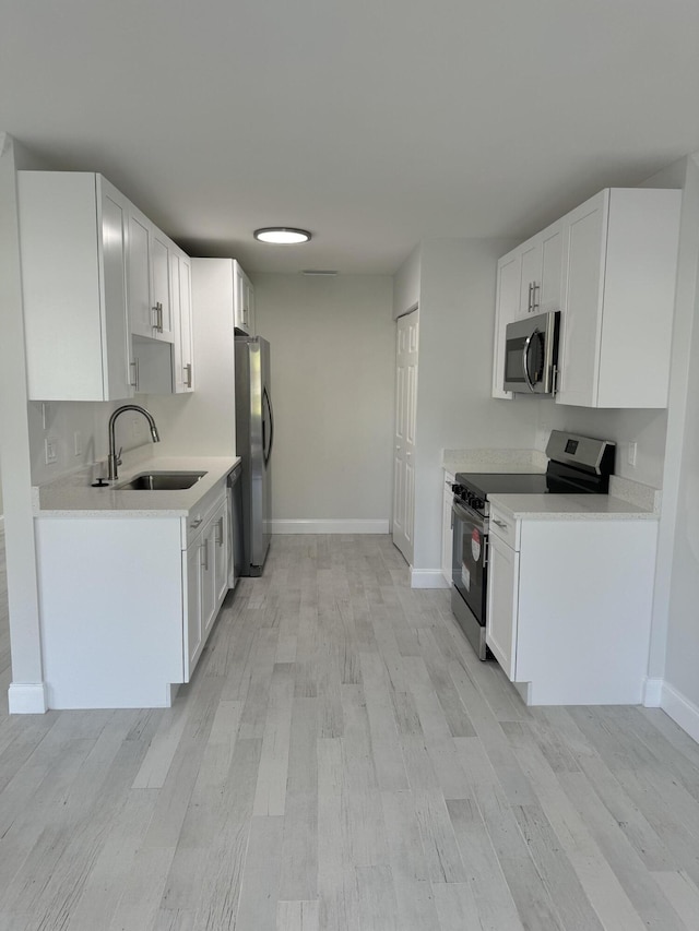 kitchen with light hardwood / wood-style floors, white cabinetry, stainless steel appliances, and sink