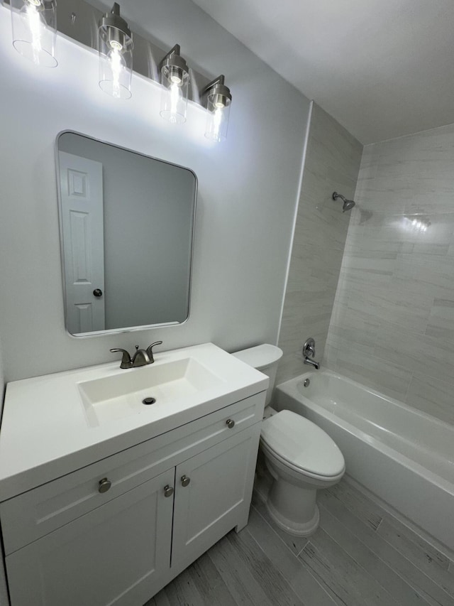 full bathroom with toilet, vanity, tiled shower / bath, and wood-type flooring