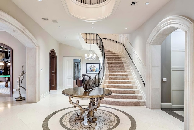 foyer with a high ceiling, an inviting chandelier, and light tile patterned floors