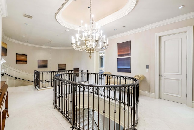 corridor with crown molding, a chandelier, and a raised ceiling