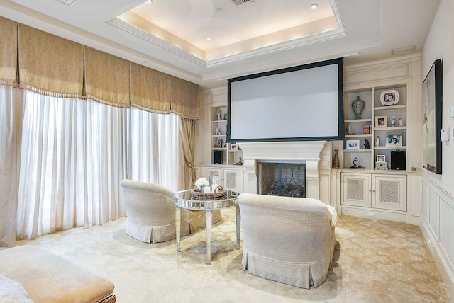 home theater room featuring a raised ceiling, built in features, and carpet flooring