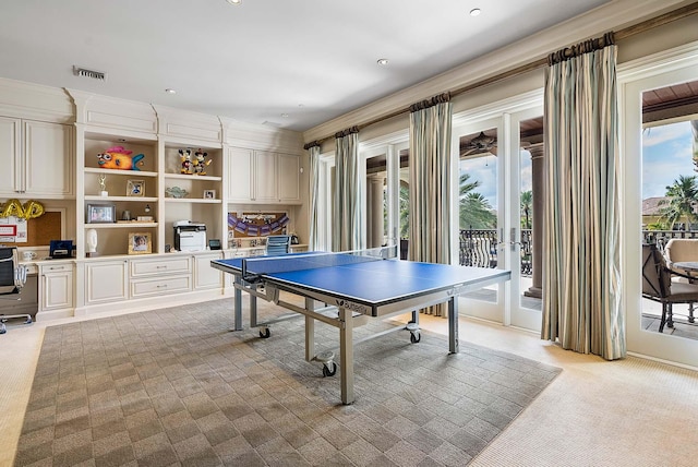 rec room featuring ornamental molding, light carpet, and built in desk