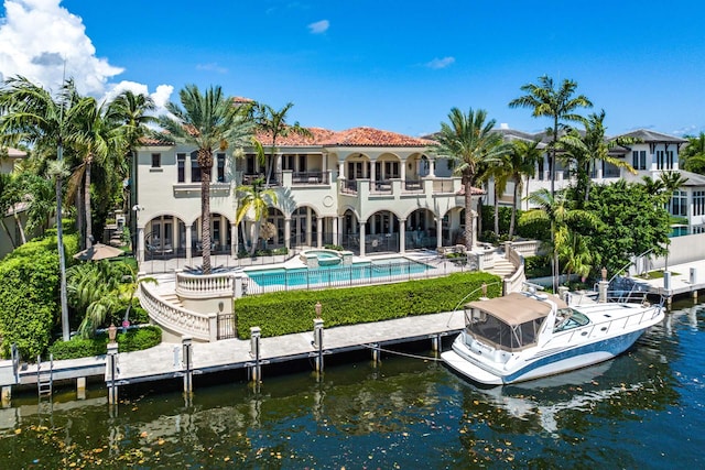 back of property with a community pool, a water view, a balcony, and a patio area